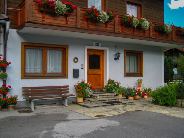 Hauseingang mit Holzbalkon und Blumen